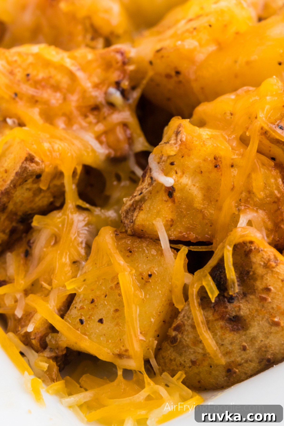 Crispy Cheesy Air Fryer Potatoes 11 A vibrant close-up of seasoned air fryer cheesy potatoes, showcasing their golden crisp exterior and melted, savory cheese.