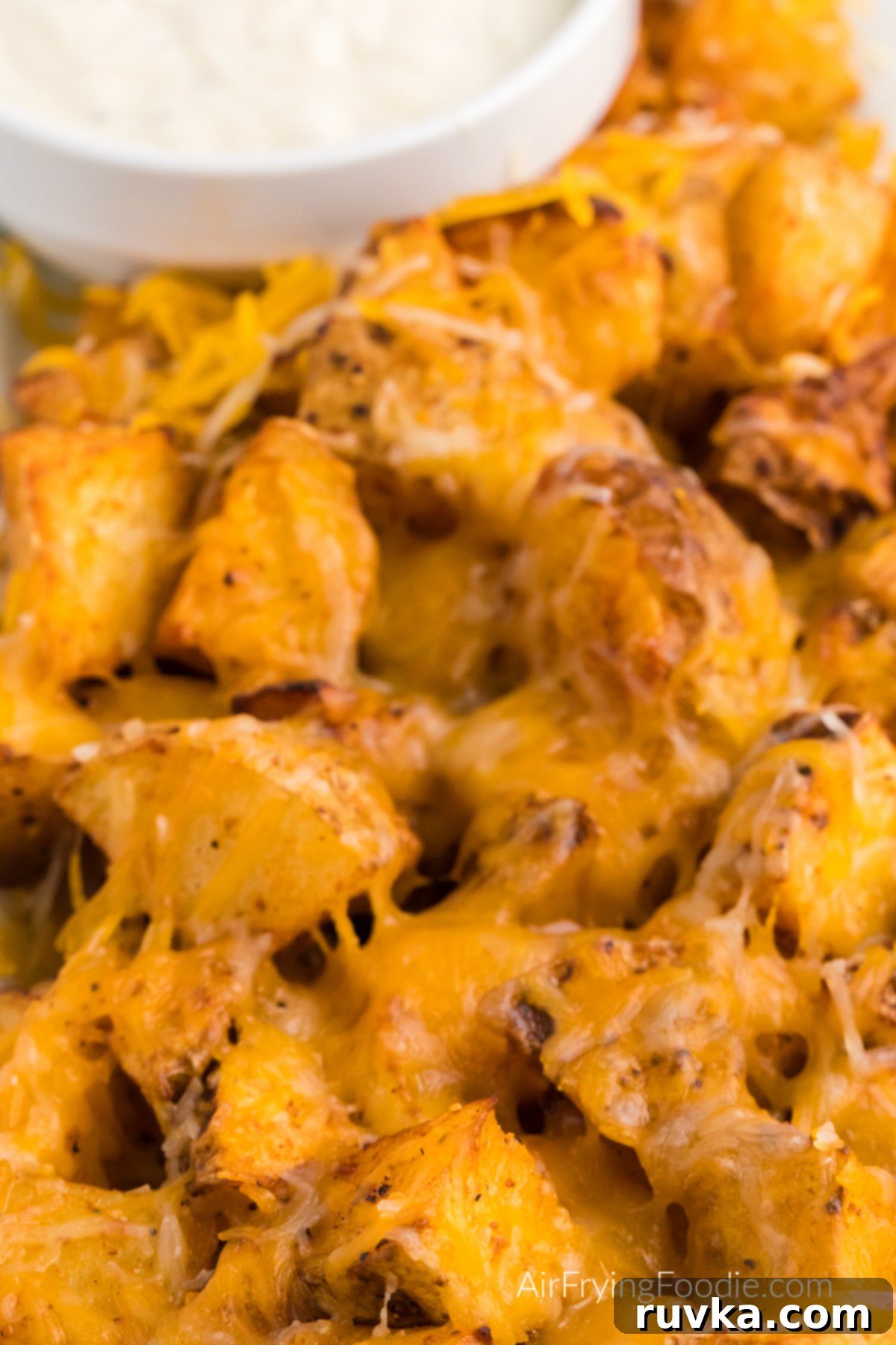 Crispy Cheesy Air Fryer Potatoes 10 A close-up view of golden, crispy air fryer cheesy potatoes, highlighting the perfectly melted cheese and savory seasoning.