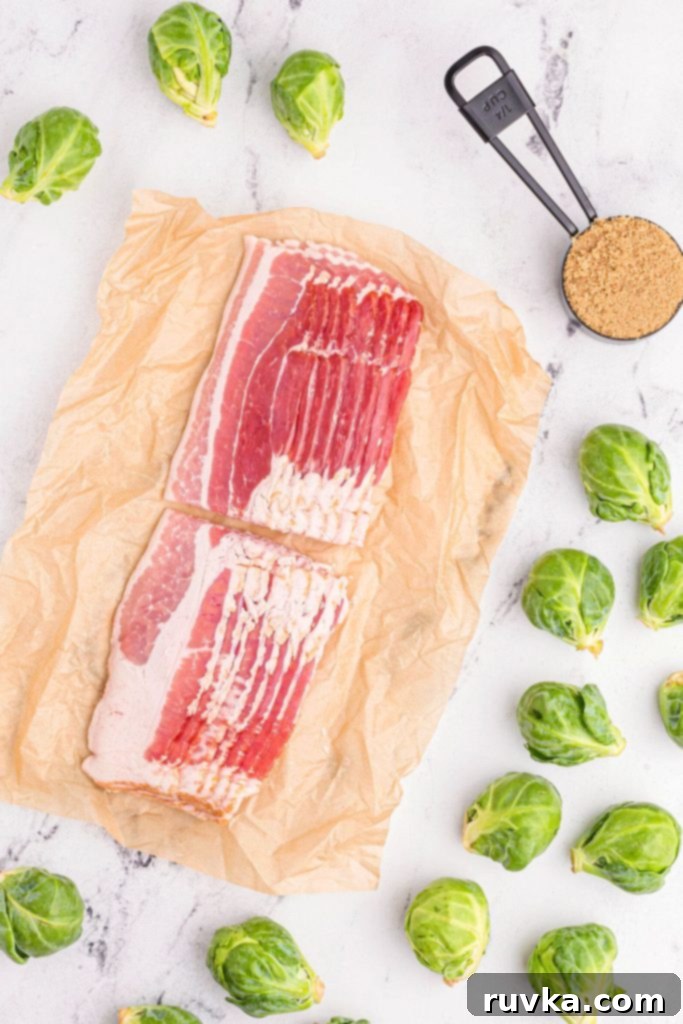 Crispy Air Fryer Bacon Brussels Bites 3 Ingredients on a white marble table of bacon, brussels sprouts, and brown sugar.