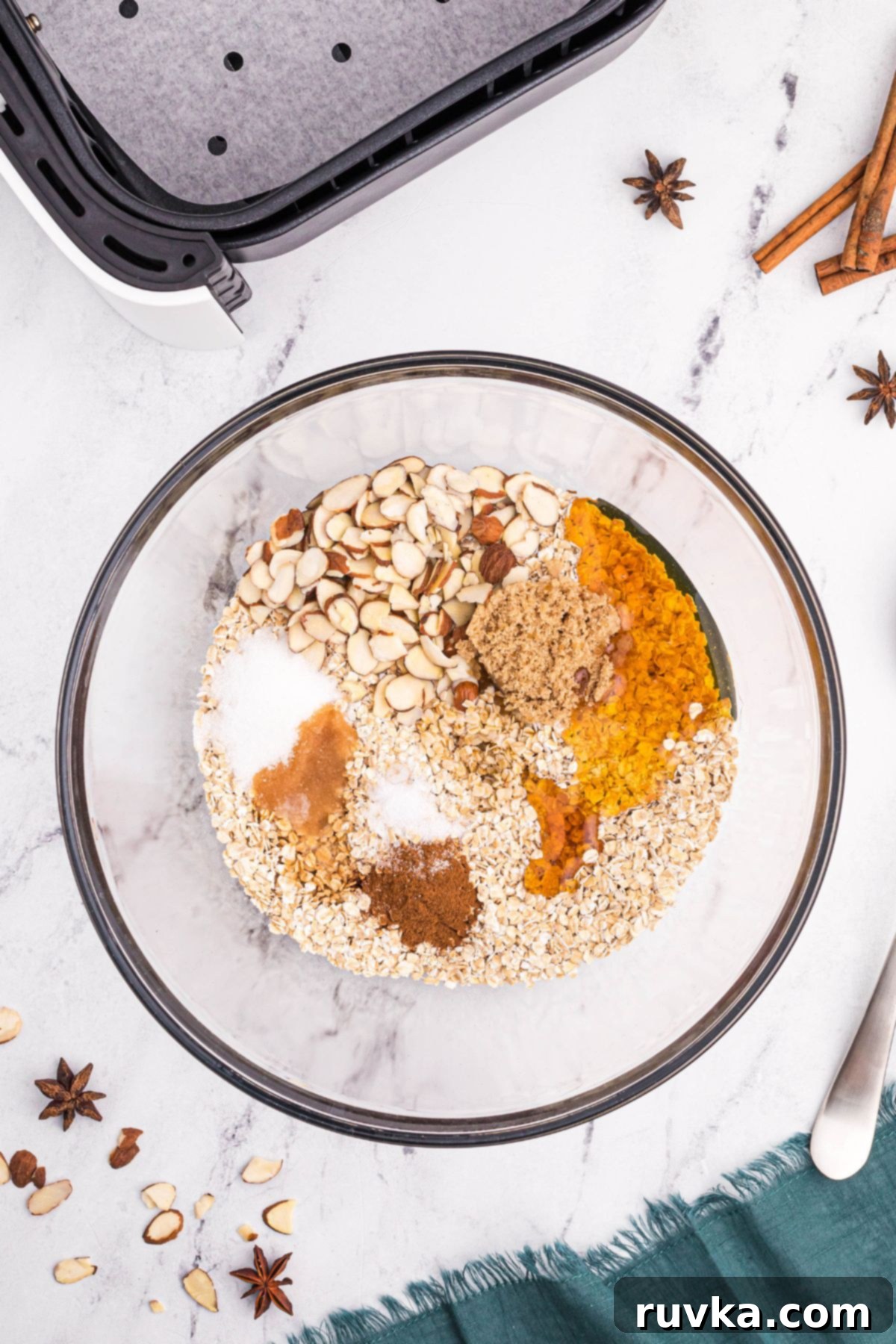 Easy Air Fryer Granola 4 Oats, with sugar, honey, and spices before mixing together in a clear glass bowl