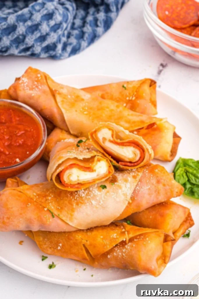 Crispy Air Fryer Pizza Egg Rolls 2 Golden crispy pizza filled egg rolls on a white plate with red dipping sauce.