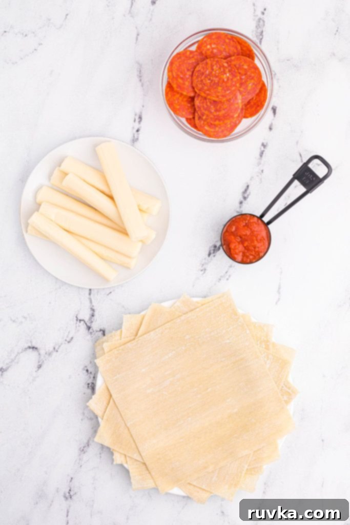 Crispy Air Fryer Pizza Egg Rolls 3 Cheese, egg roll wrappers, sauce and pepperonis on a white marble table.