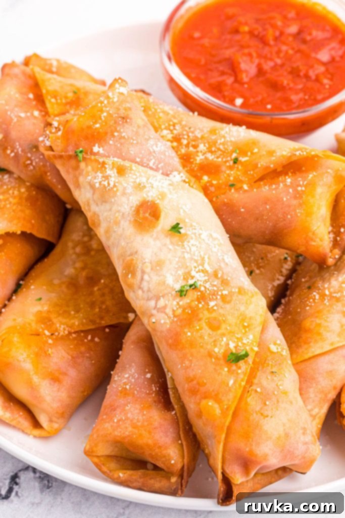 Crispy Air Fryer Pizza Egg Rolls 9 Golden crispy egg rolls stacked on a white plate with red dipping sauce.