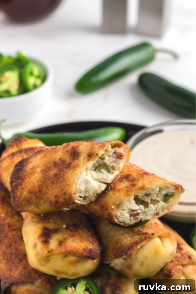 Air Fryer Jalapeno Popper Crunch Rolls 8 Several perfectly golden and crispy Air Fryer Jalapeno Popper Egg Rolls, showing the rich cream cheese and chopped jalapeno filling.