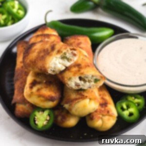 Air Fryer Jalapeno Popper Crunch Rolls 9 Golden crispy cream cheese egg rolls on a black plate, perfectly cooked in an air fryer.