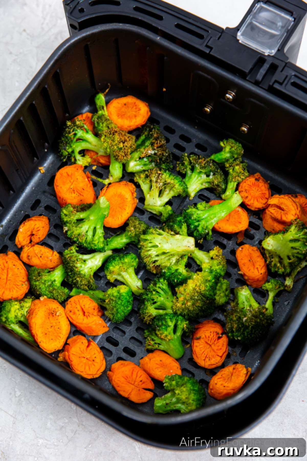Crispy Air Fryer Broccoli and Carrots 8 Seasoned and air fried carrots and broccoli in the basket of the air fryer.