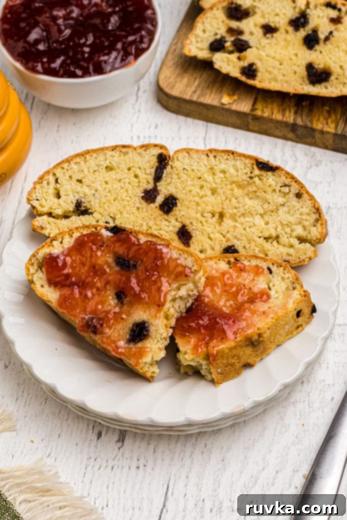 Easy Air Fryer Irish Soda Bread 10 Golden slices of Irish Soda Bread with jam on top, on a white plate.