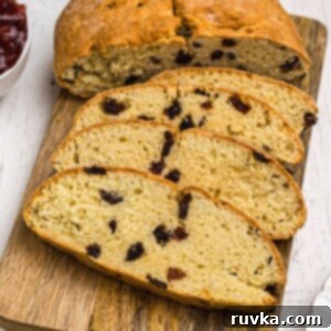 Easy Air Fryer Irish Soda Bread 12 Golden Irish Soda bread filled with raisins, slices on a wooden cutting board.
