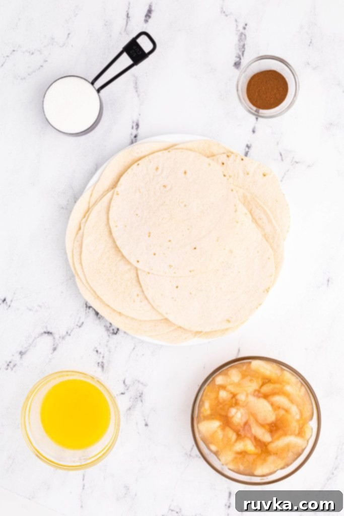 Crispy Air Fryer Apple Pie Taquitos 3 Tortillas, apple pie filling, butter, cinnamon and sugar on a white marble table.