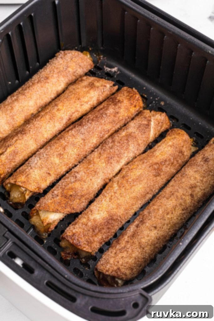 Crispy Air Fryer Apple Pie Taquitos 8 Golden brown and crispy taquitos filled with apple pie filling in the air fryer basket.