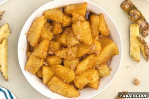 Air-Fried Caramelized Pineapple 2 Golden juicy pineapple coated in juices and brown sugar, served on a white plate.