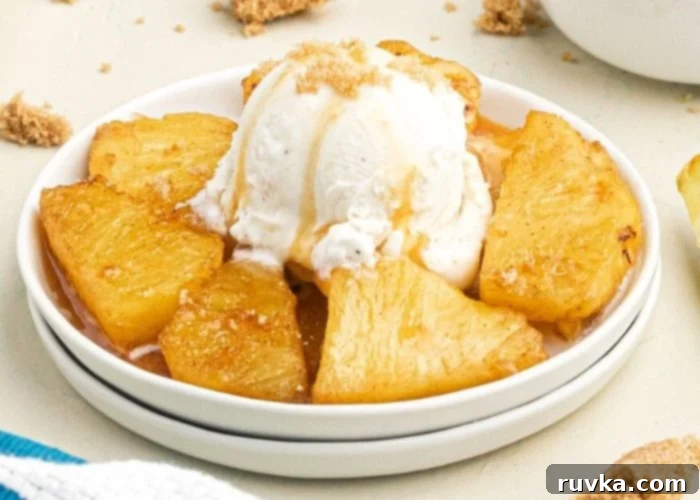 Air-Fried Caramelized Pineapple 3 Juicy golden pineapple in juices, topped with vanilla ice cream and caramel sauce, served on a white plate.