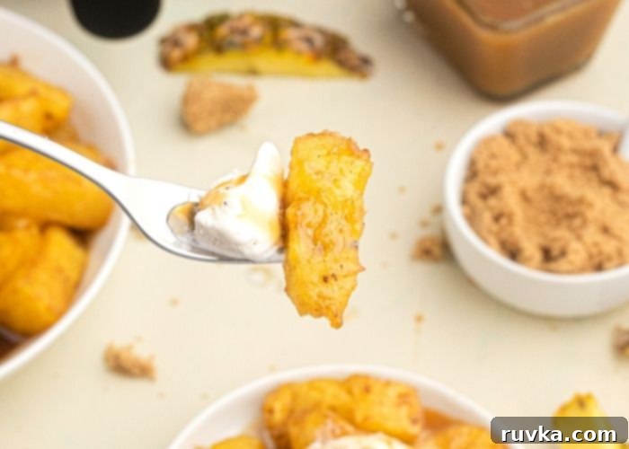 Air-Fried Caramelized Pineapple 6 Juicy piece of golden pineapple on a fork, with a small bite of vanilla ice cream.