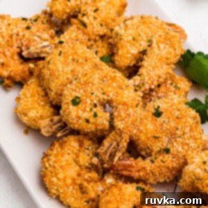 Crispy Air Fryer Breaded Shrimp 11 Golden breaded shrimp on a white plate garnished with parsley.