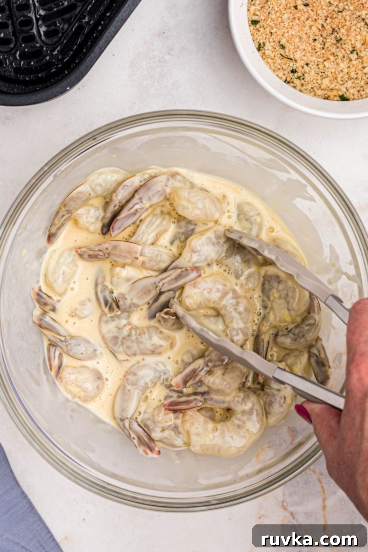 Crispy Air Fryer Breaded Shrimp 5 Shrimp tossed with flour and egg batter in a clear glass bowl.