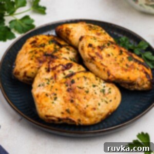 Tender Air Fryer Yogurt Chicken 9 Golden juicy chicken breasts on a blue plate with parsley garnish.