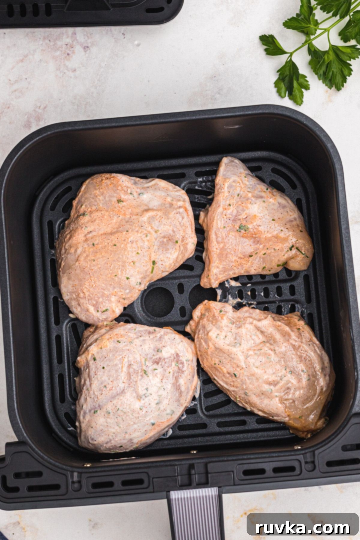 Tender Air Fryer Yogurt Chicken 5 Uncooked chicken coated with yogurt marinade in the air fryer basket.