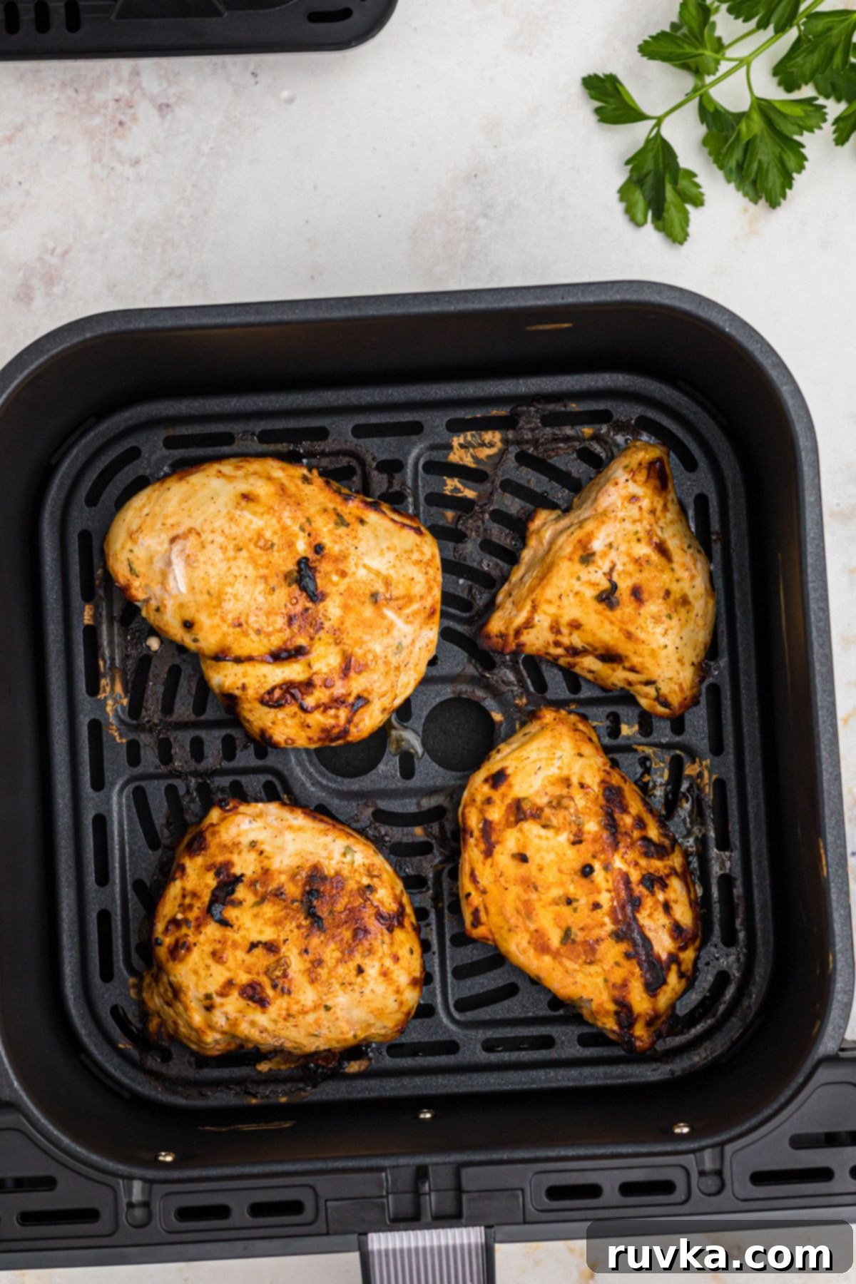 Tender Air Fryer Yogurt Chicken 6 Golden marinated chicken breasts in the air fryer basket after being cooked.