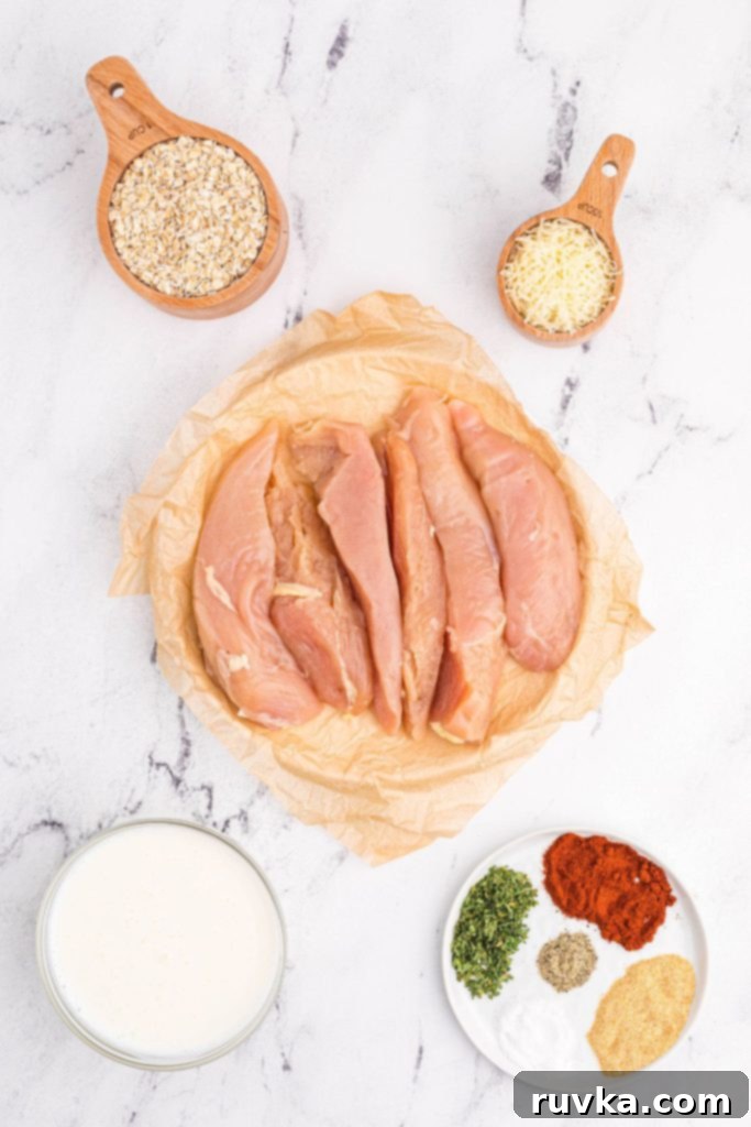 Crispy Golden Oat Air Fryer Chicken 3 Ingredients measured on a white marble table with uncooked chicken in the center of ingredients.