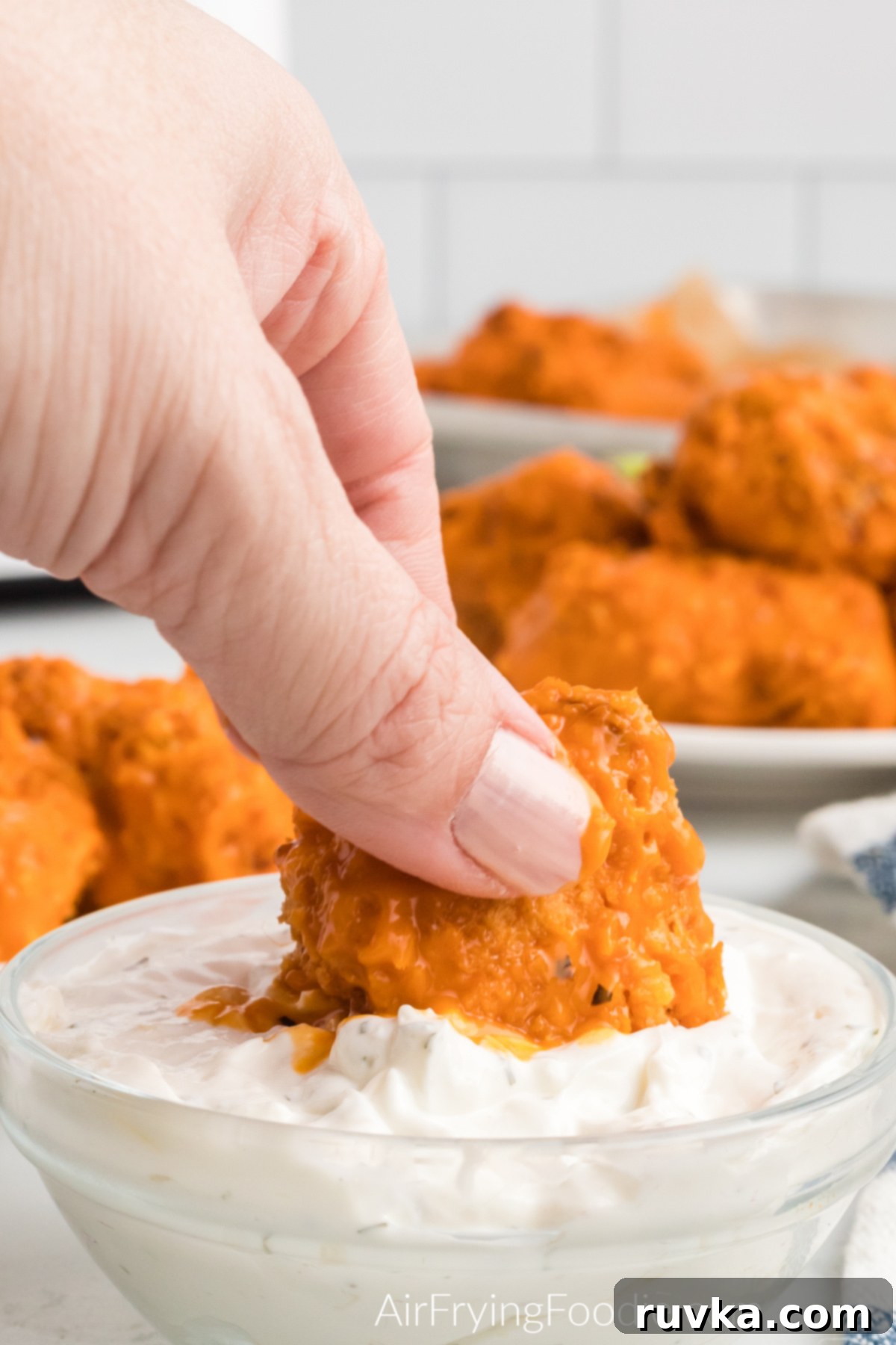 Crispy Air Fryer Boneless Wings 11 Air fryer boneless wing being dipped into sauce before eating.