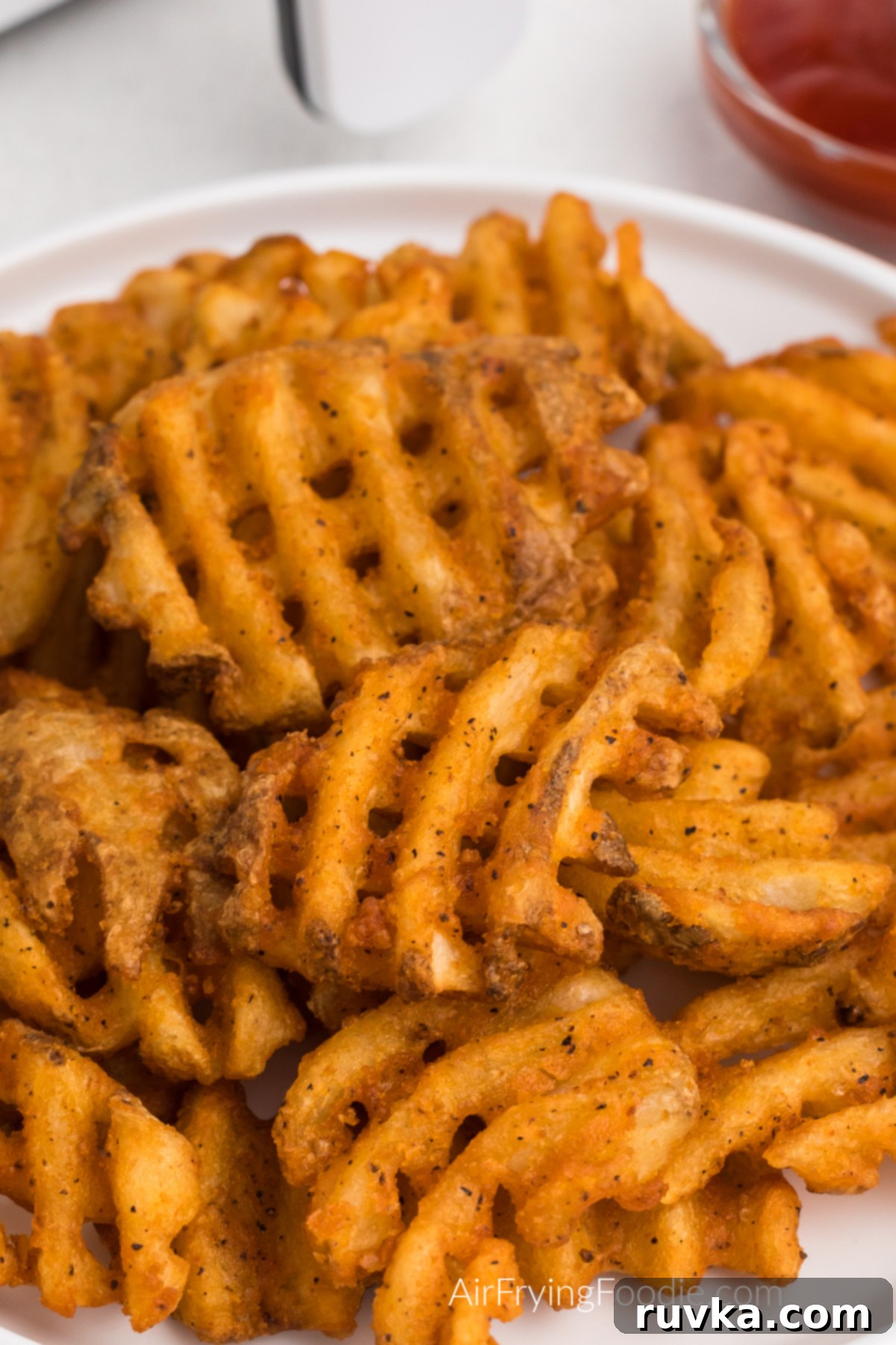 Crispy Air Fryer Waffle Fries 2 Seasoned waffle fries made in the air fryer and served on a white plate.