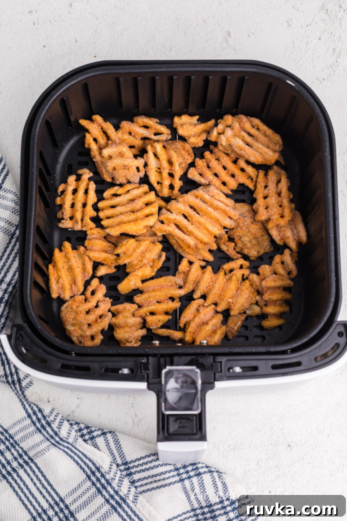 Crispy Air Fryer Waffle Fries 4 frozen waffle fries in the basket of the air fryer.