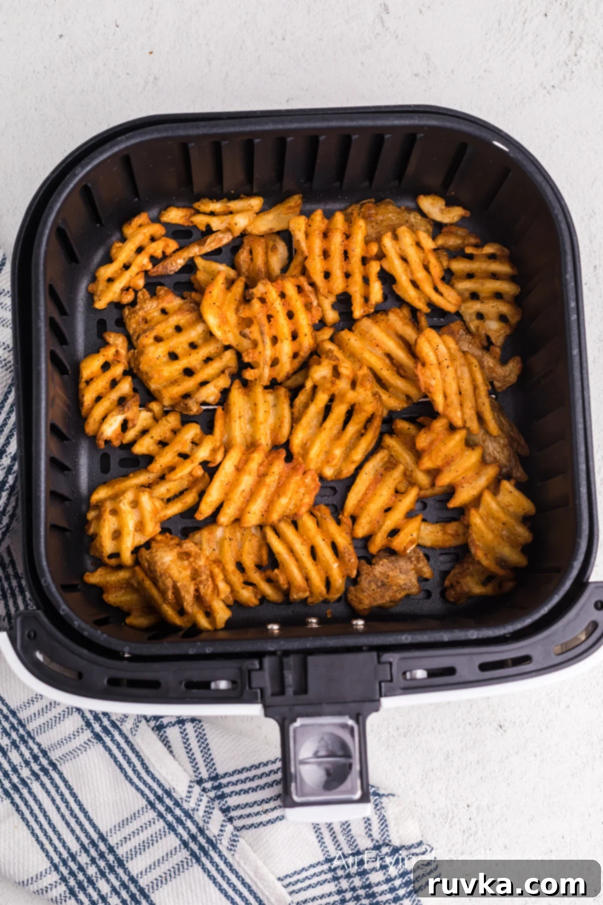 Crispy Air Fryer Waffle Fries 5 Air fried frozen waffle fries in the basket of the air fryer, ready to serve.