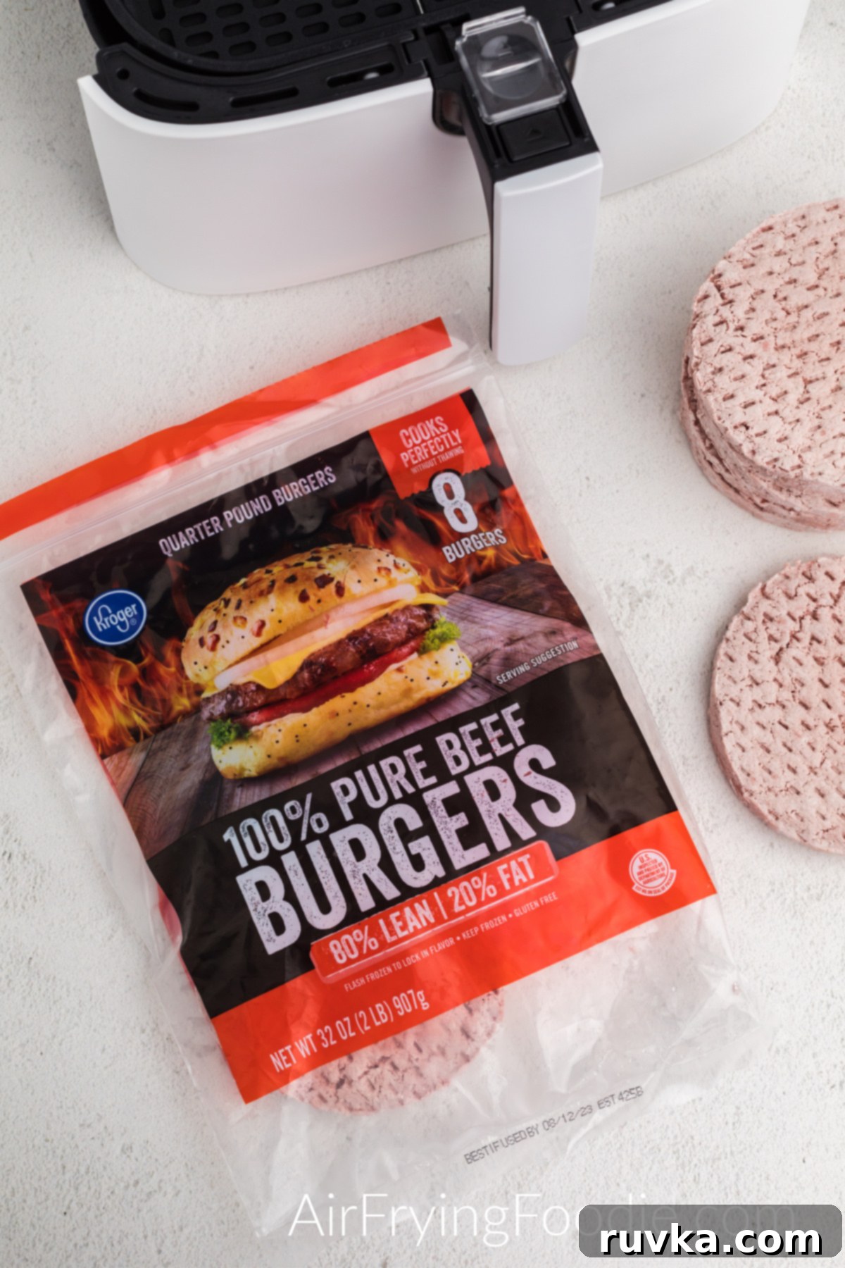 Perfect Air Fryer Frozen Burgers 3 Frozen burger patties and air fryer basket on a table top.