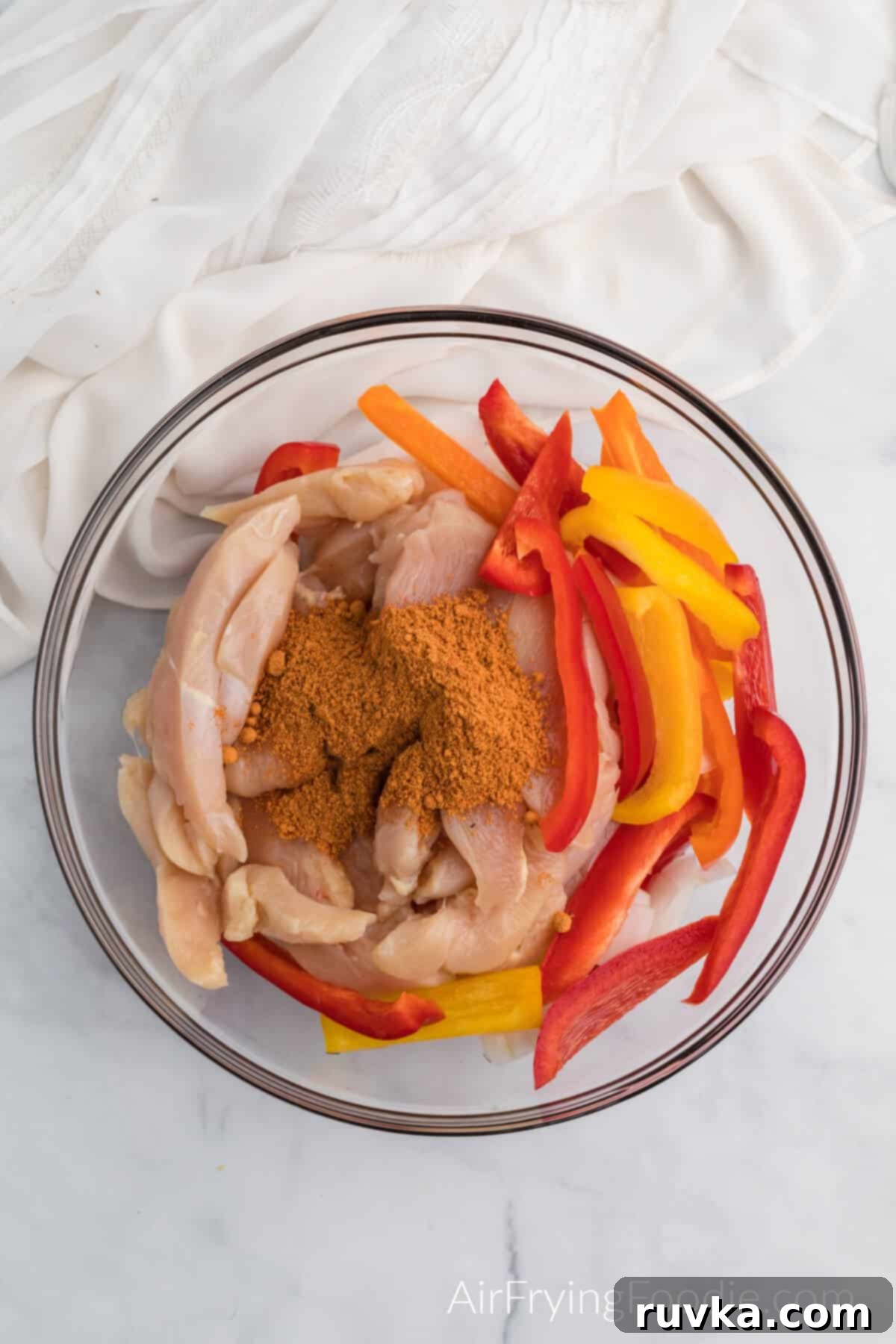 Easy Air Fryer Chicken Fajitas 4 Bowl full of sliced chicken, onions, and bell peppers topped with taco seasoning.