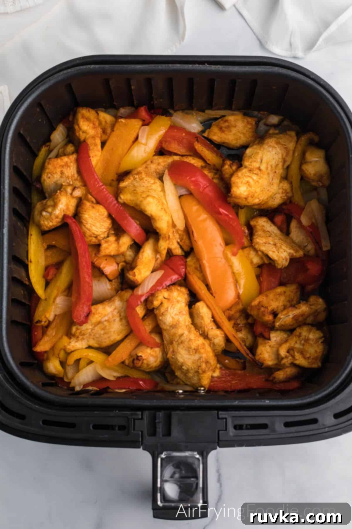 Easy Air Fryer Chicken Fajitas 6 Air fried chicken fajita meat, peppers, and onions in the basket of the air fryer.