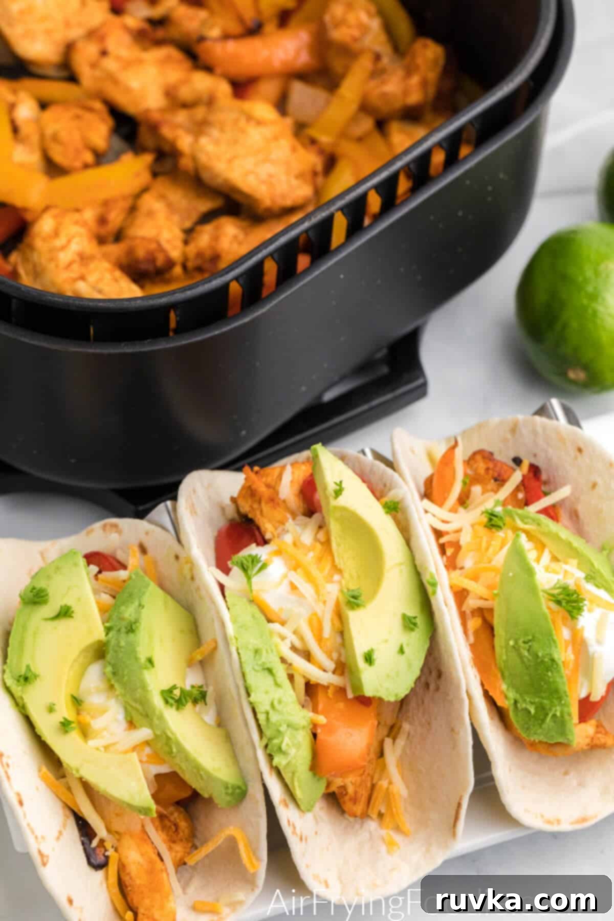 Easy Air Fryer Chicken Fajitas 7 Chicken fajitas served in flour tortillas topped with cheese, avocado slices, and fresh parsley flakes.
