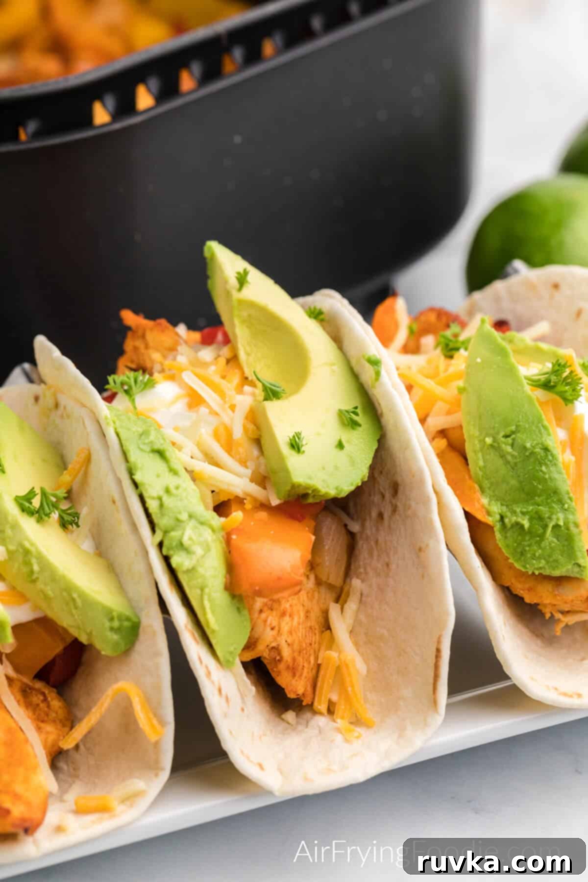 Easy Air Fryer Chicken Fajitas 8 air fried chicken fajitas served on flour tortillas with sliced avocado, cheese, and fresh cilantro.