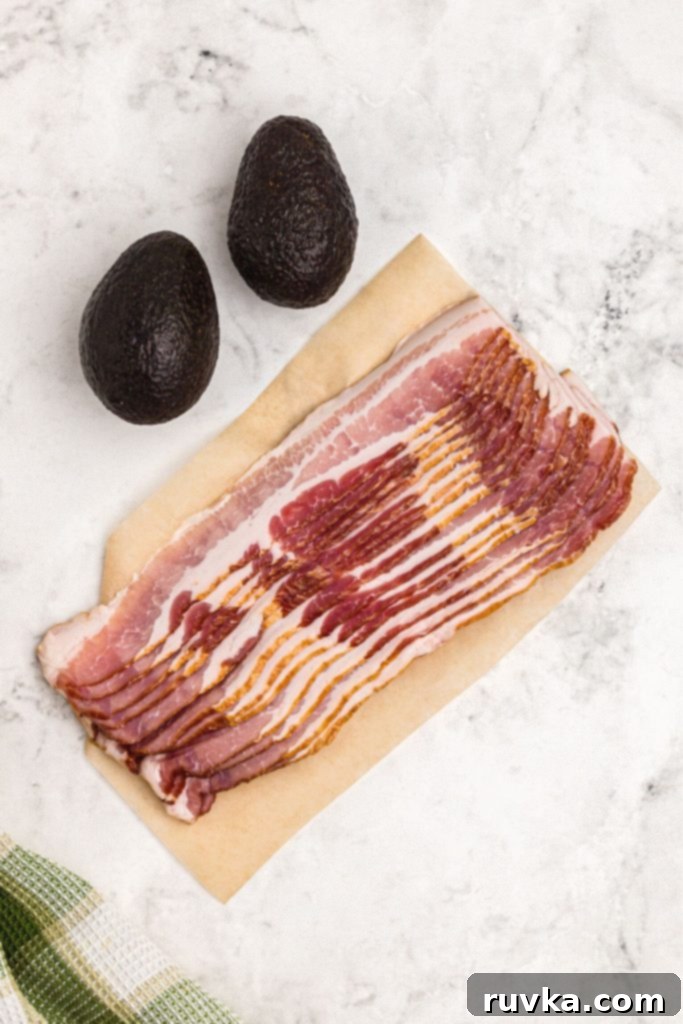 Air Fryer Bacon Wrapped Avocado Perfection 3 Bacon and avocados on a white marble table.