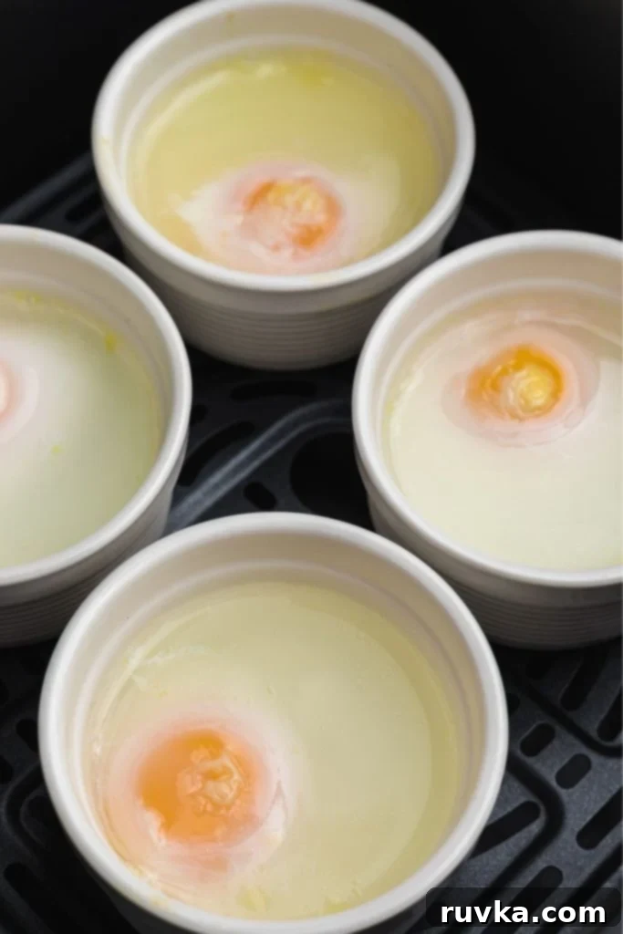 Perfect Air Fryer Poached Eggs 6 Poached eggs in ramekins in the air fryer basket.