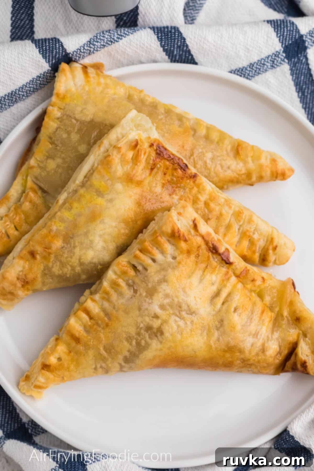 Crispy Air Fryer Apple Turnovers 8 Close up photo of air fryer apple turnovers on a white plate, ready to be enjoyed.