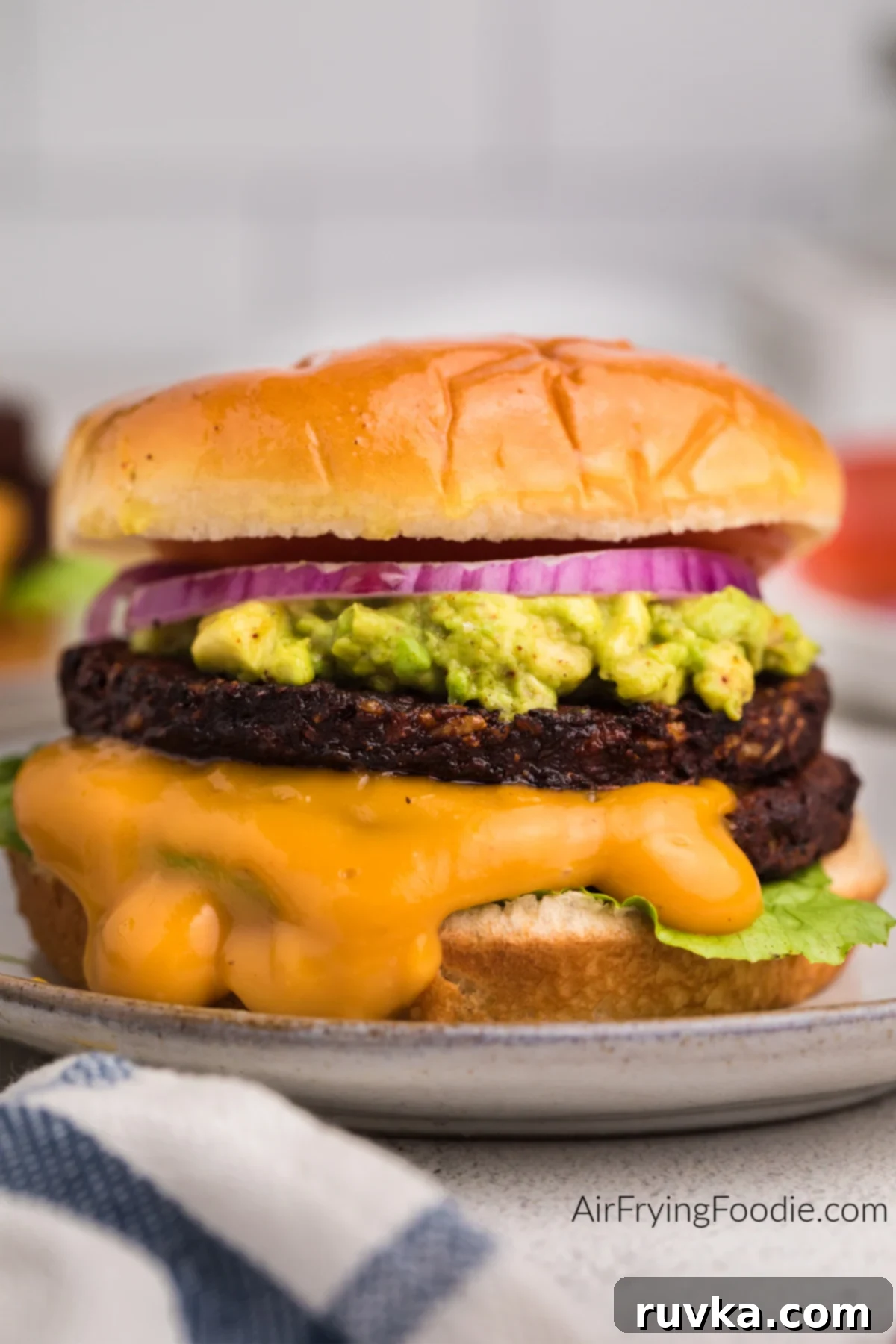 Crispy Air Fryer Black Bean Burger 2 Black bean burger made in the air fryer topped with mashed avocado, onion, tomato, and sauce.