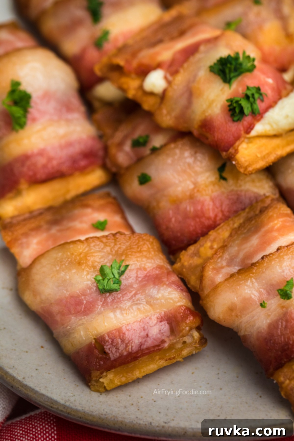 Air Fryer Bacon Cream Cheese Cracker Bites 11 Bacon wrapped cream cheese crackers on a plate, ready to eat.