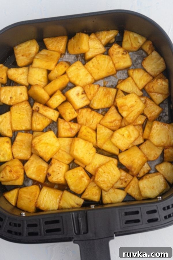 Air Fried Honey BBQ Pineapple 5 Perfectly cooked, juicy golden pineapple in the air fryer basket after being cooked in honey and bbq sauce, showing slight caramelization.