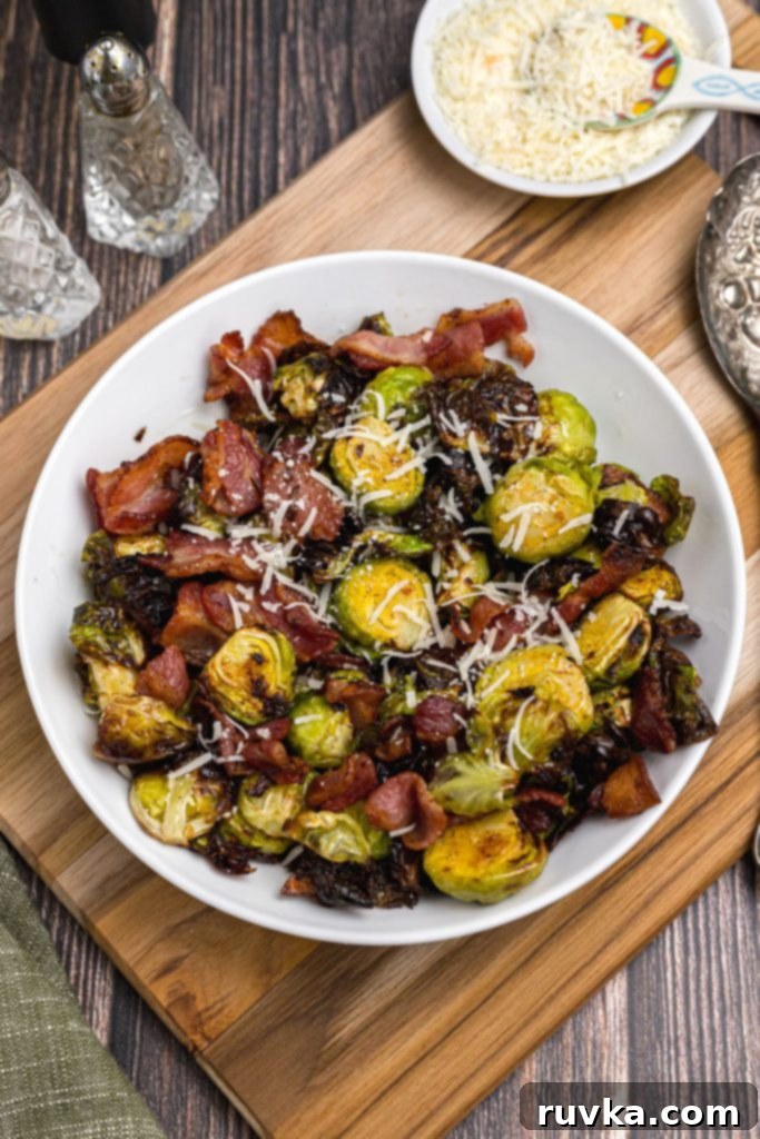 Crispy Air Fryer Brussels Sprouts and Bacon 2 Green Brussels sprouts tossed with pieces of crispy bacon and shredded parmesan cheese in a white bowl.