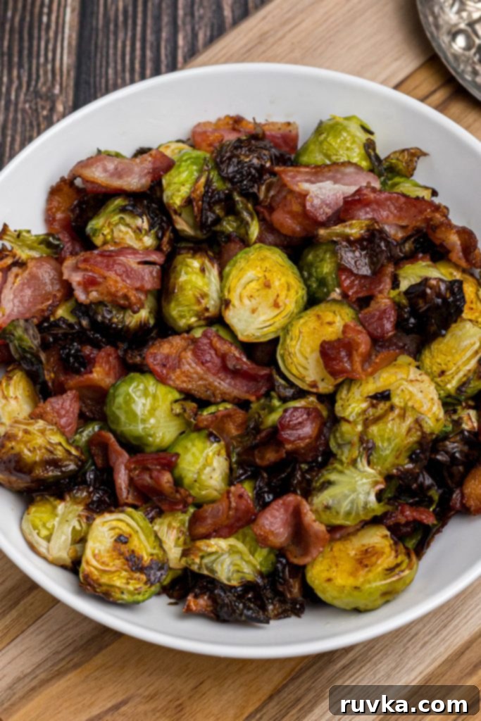 Crispy Air Fryer Brussels Sprouts and Bacon 4 Crispy green cooked brussels sprouts tossed with crispy pieces of bacon in a white bowl on a wooden table.