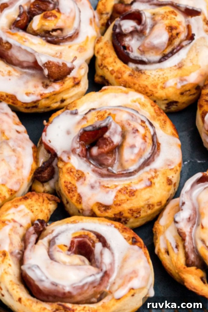 Air Fried Bacon Cinnamon Delights 2 Close up photo of golden cinnamon roll wrapped around a slice of bacon and then drizzled with glaze frosting.