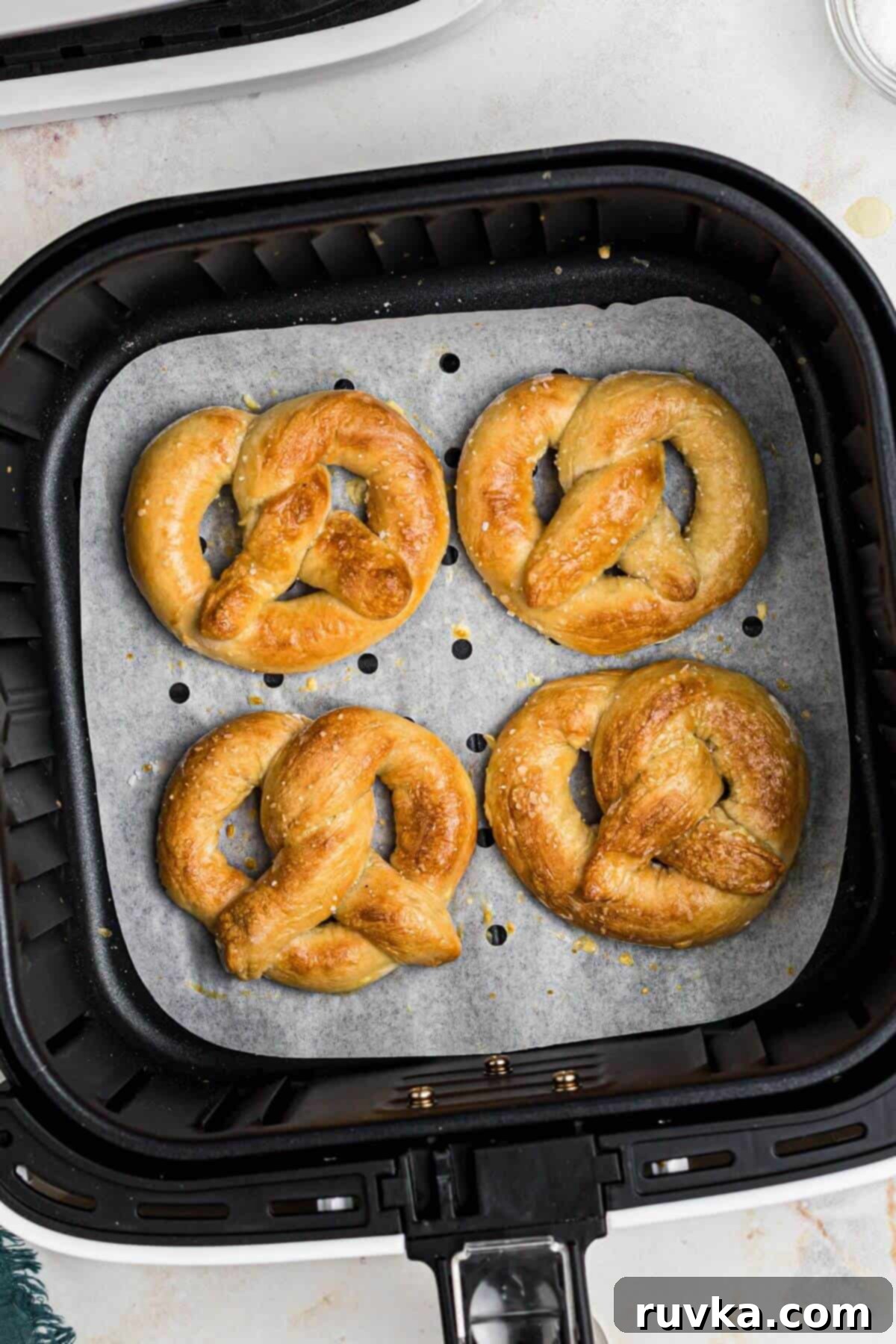 Perfectly Soft Air Fryer Pretzels 9 Golden brown soft pretzels in the air fryer basket after being cooked.