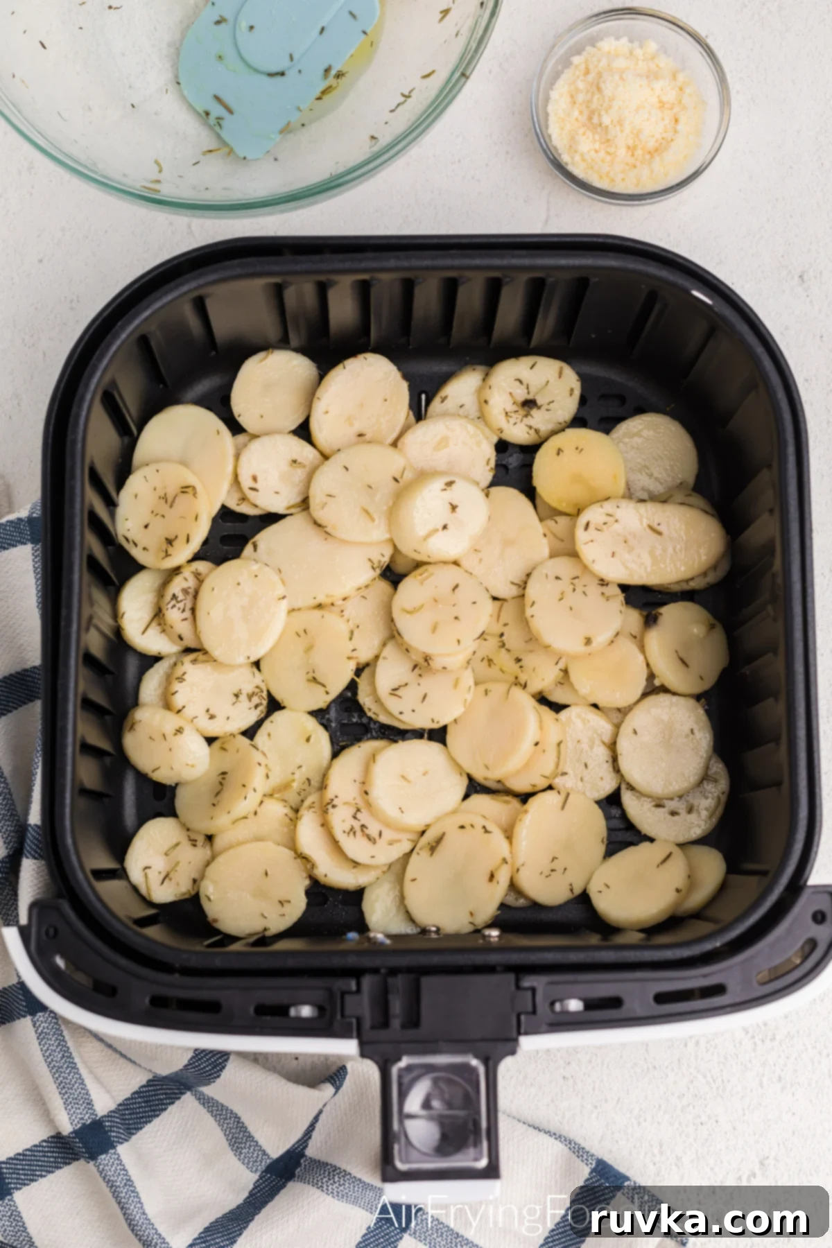 Sliced potatoes neatly arranged in an air fryer basket, ready for cooking to achieve optimal crispness.