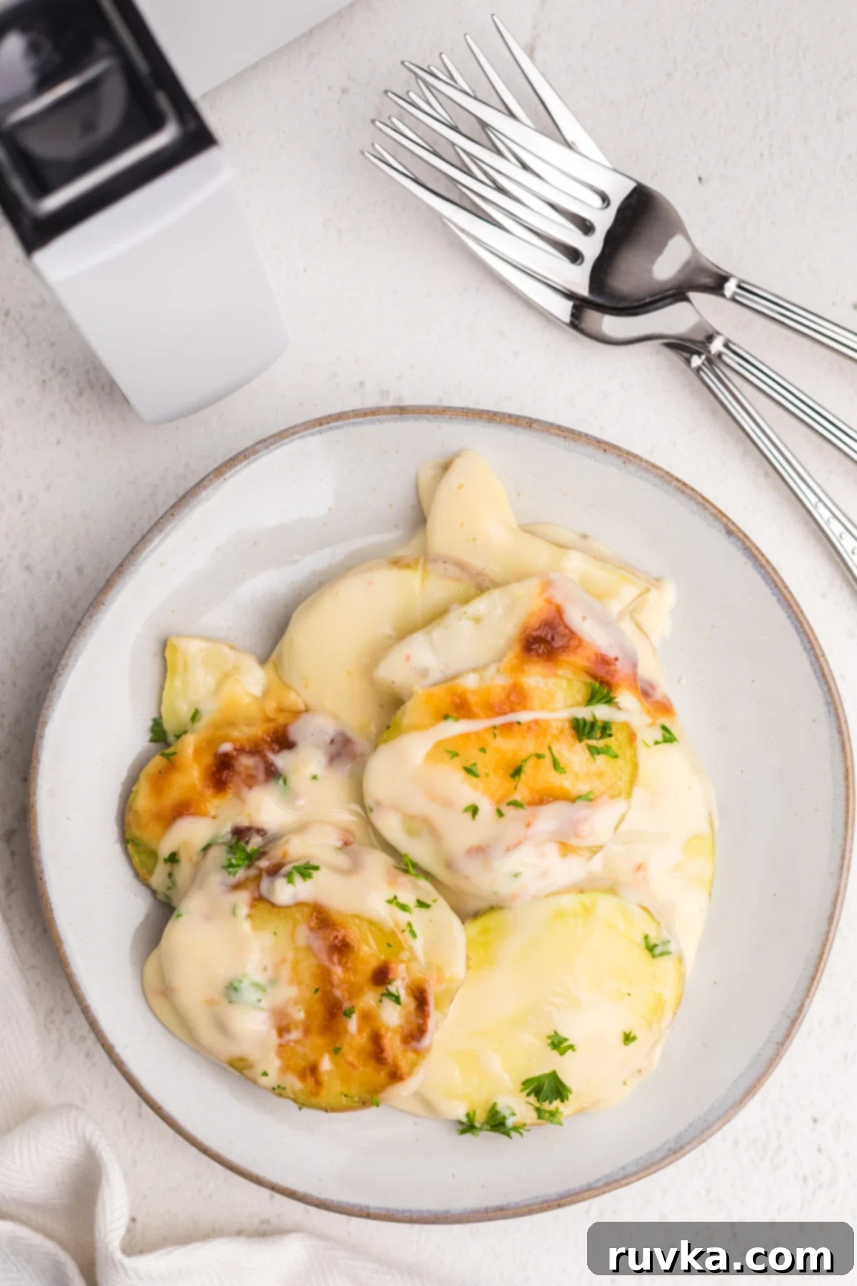 Easy Cheesy Air Fryer Scalloped Potatoes 13 A dish of golden-brown scalloped potatoes, fresh from the air fryer, beautifully garnished with fresh parsley and served on a plate.