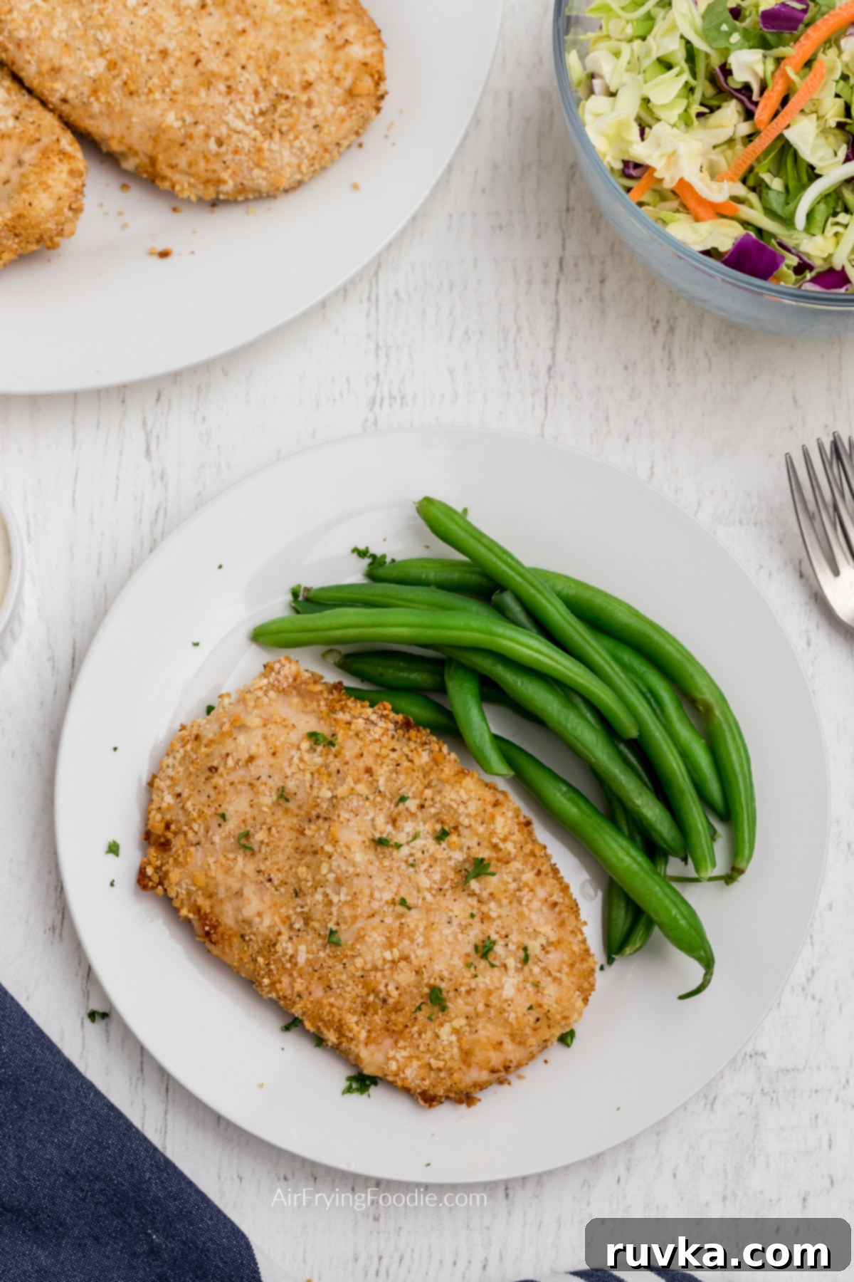 Crispy Air-Fried Chicken Breast 9 Overhead shot of air fryer fried chicken breast and green beans on a white plate ready to serve.