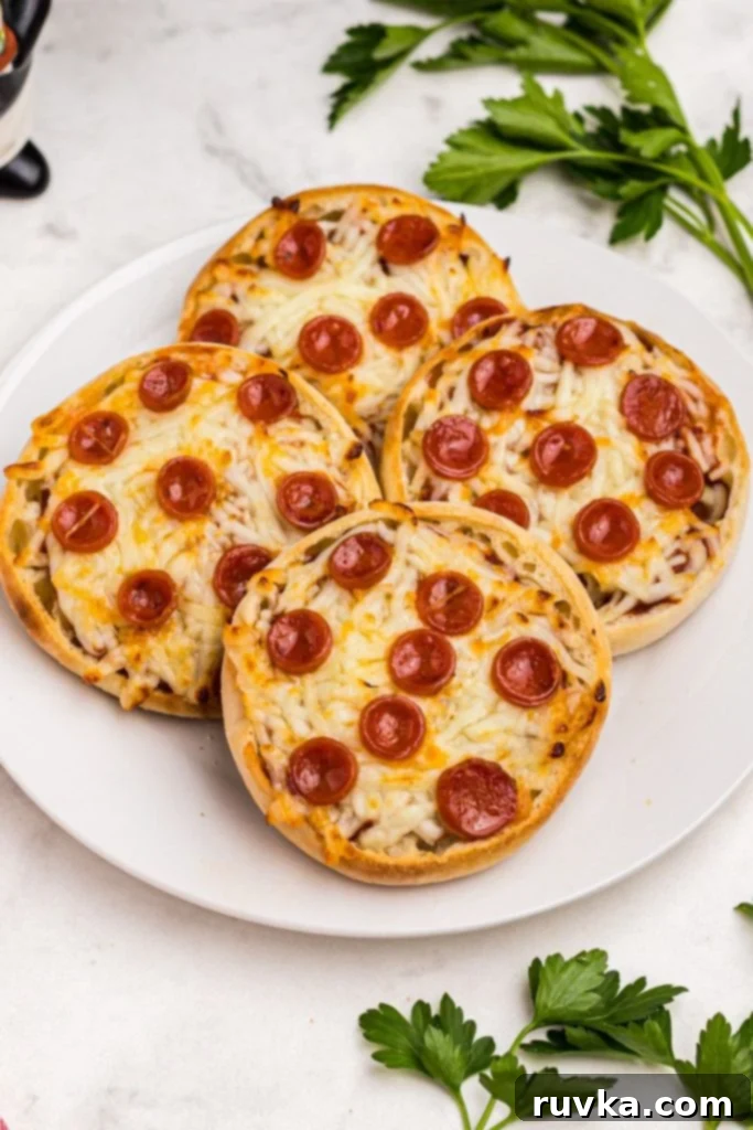 Easy Air Fryer English Muffin Pizzas 8 Golden crispy English Muffin Pizzas on a white plate, elegantly garnished with fresh parsley for a vibrant touch.