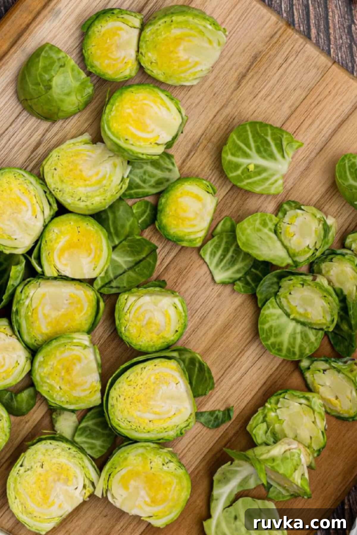 The Best Air Fryer Parmesan Brussels Sprouts 3 Brussels sprouts on a cutting board sliced in half and with leaves removed.