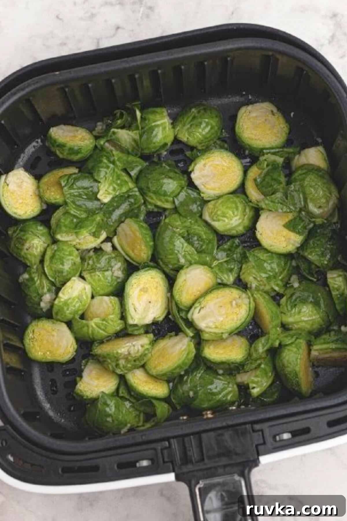 The Best Air Fryer Parmesan Brussels Sprouts 5 Prepared Brussels sprouts in the basket of the air fryer, ready to be cooked.