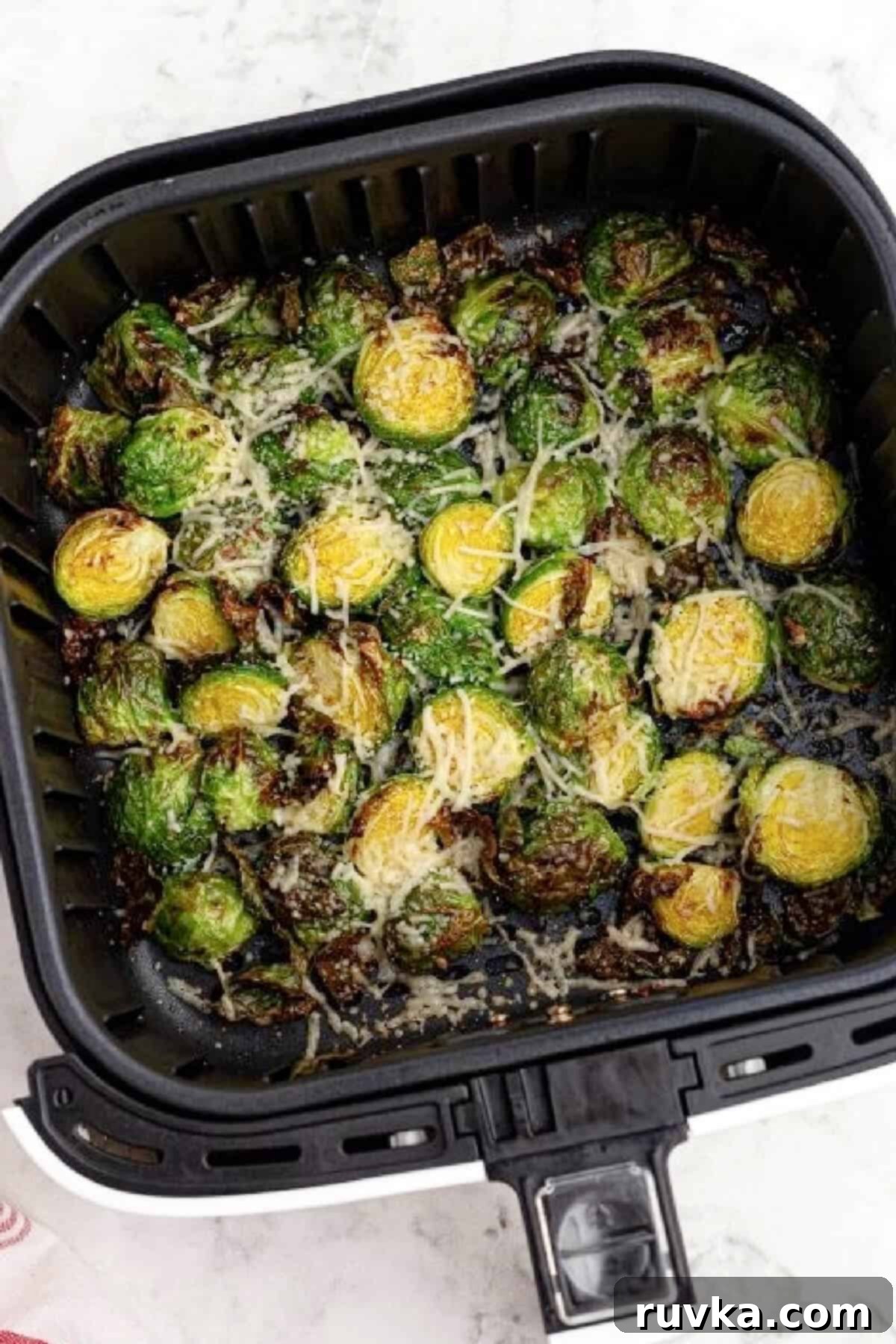 The Best Air Fryer Parmesan Brussels Sprouts 6 Brussels sprouts air fried and topped with parmesan cheese in the basekt of the air fryer.