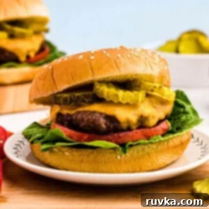 Air Frying Made Simple 27 Juicy hamburger topped with cheese, lettuce, tomato and pickles, on a bun.